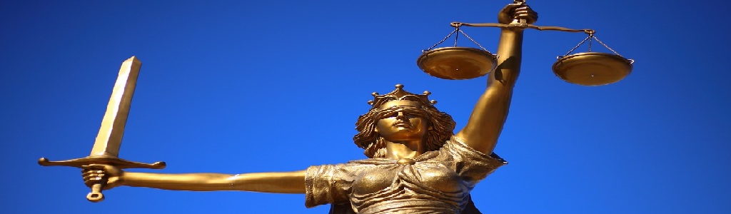 Estatua de la Diosa de la Justicia con los ojos vendados, sosteniendo una balanza y una espada, representando la imparcialidad legal y la justicia.