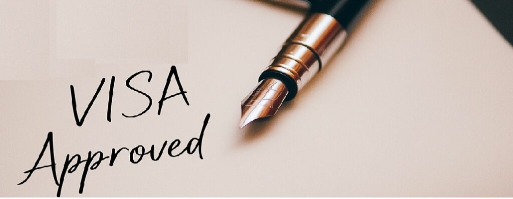 Close-up of a paper with “Visa Approved” written by a fountain pen and a U.S. Immigration Visa stamp.