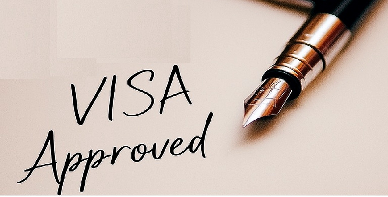 Close-up of a paper with “Visa Approved” written by a fountain pen and a U.S. Immigration Visa stamp.