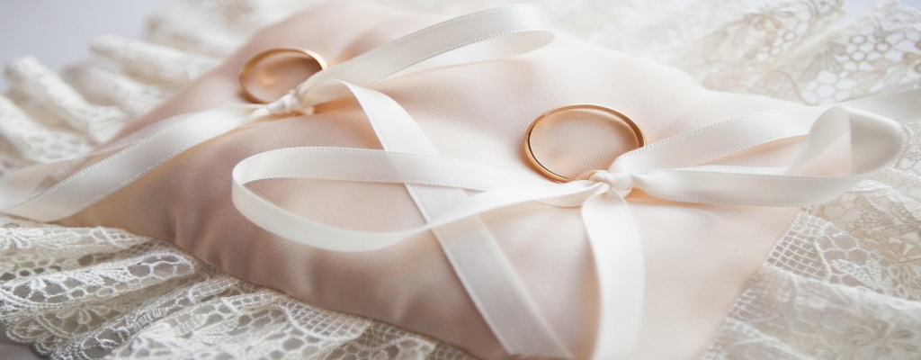 Two wedding rings tied with a white ribbon on a small white pillow, symbolizing U.S. Immigration Visa marriage process.
