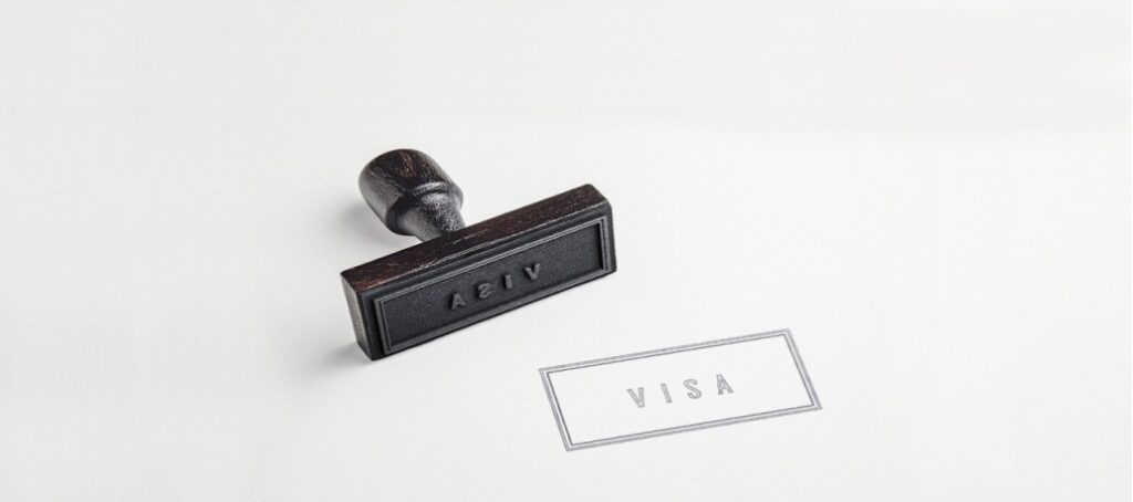 Close-up of a visa stamp and the word “Visa” printed on a document.