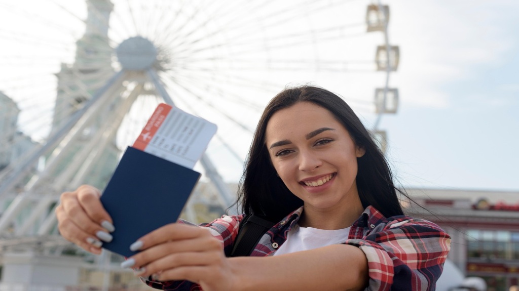 Una joven sonriente muestra su pasaporte y tarjeta de embarque a la cámara.